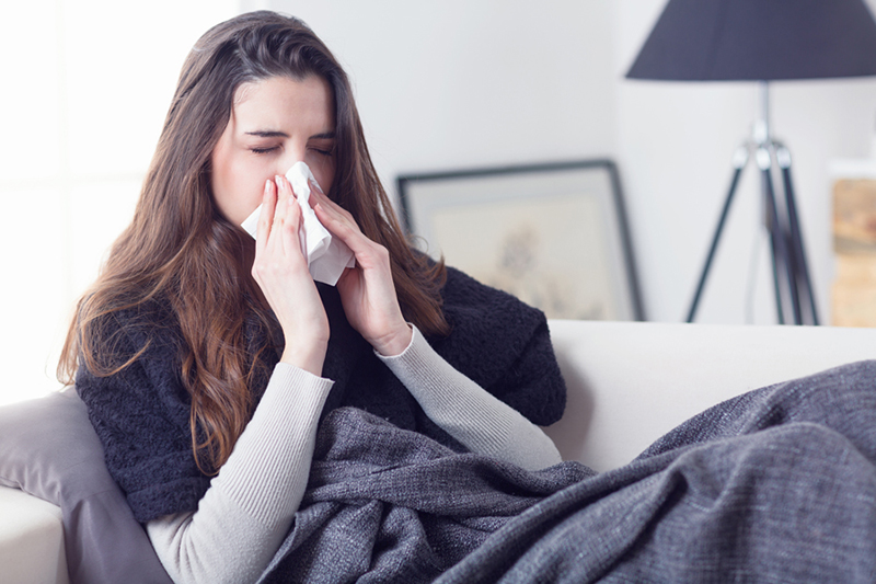 What Does Indoor Air Quality Have to Do With Allergies? Woman sneezing nose with tissue.